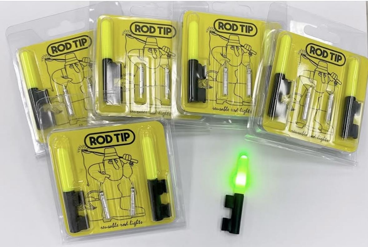 Five Rod Tip blister packs on a table with the cartoon angler mascot artwork, beside one lit, glowing green clip